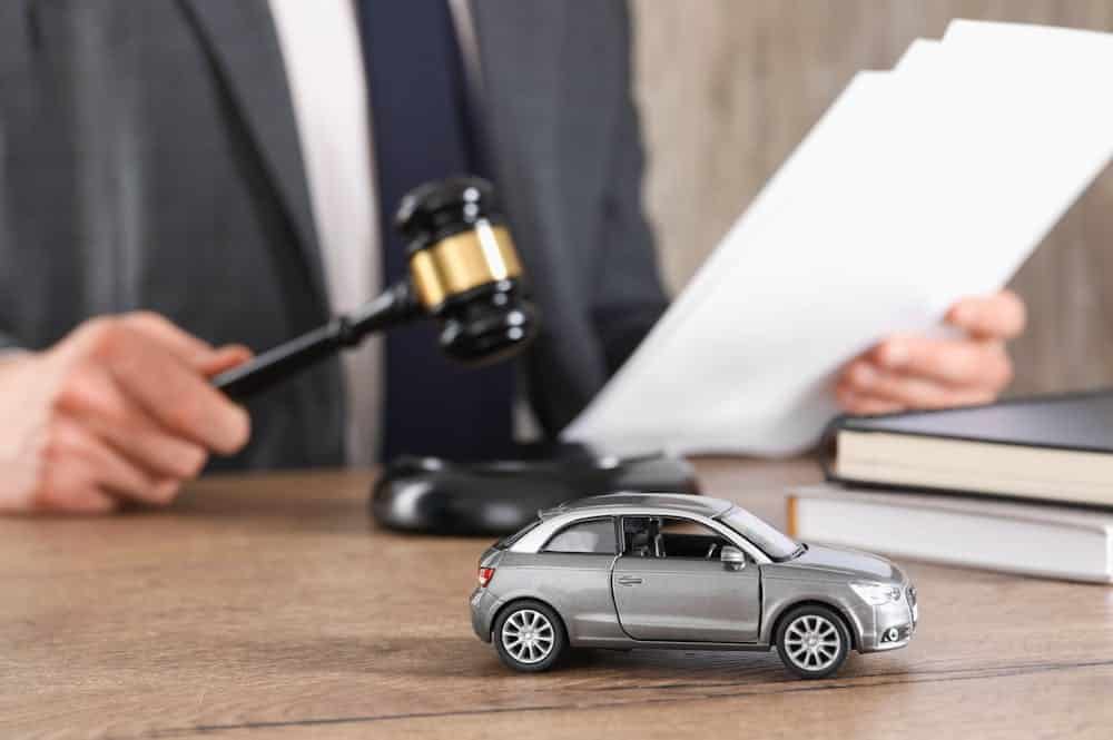 Why Should You Consult a Fort Lauderdale Car Accident Lawyer – Personal Injury Lawyer in Fort Lauderdale Miniature car and gavel on table, lawyer reading documents in background. Car accident legal concept.